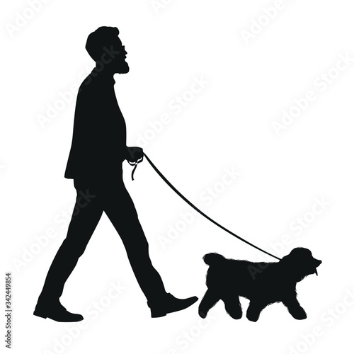 The silhouette of a man takes his dog walking