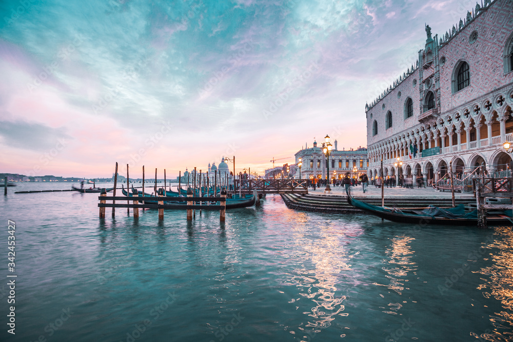 Colorful sunset in Venice, gondolas and reflections in the water