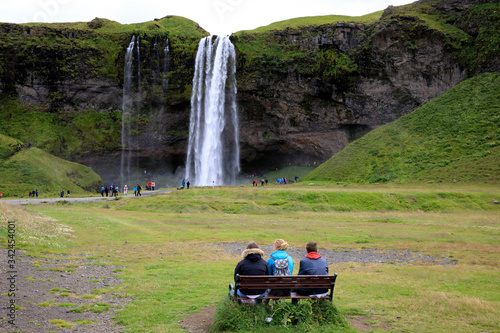 Seljalandsfoss / Iceland - August 15, 2017: Tourists relaxing on a bench near Seljalandsfoss waterfall, Iceland, Europe