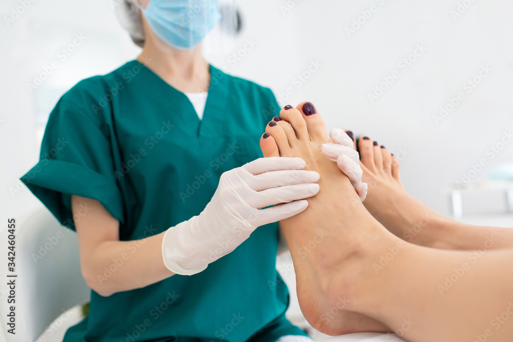Master during a pedicure. The process of professional pedicures. Master in protective mask is engaged in massage of female feet. The concept of beauty and health. Copy space Master during a pedicure. The process of professional pedicures. Master in protective mask is engaged in massage of female feet. The concept of beauty and health. Copy space