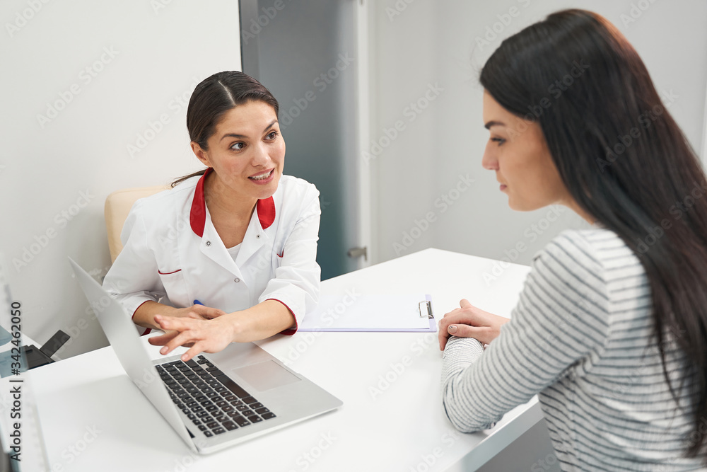 Cheerful young medical worker pointing at computer Cheerful young medical worker pointing at computer