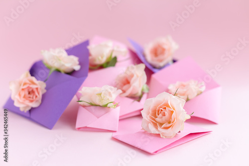 Purple and pink paper open envelopes with full small rose flowers on color background. Spring, summer concept. Romance, love notes, greeting card for March 8 International Woman's, Valentine's day © velirina