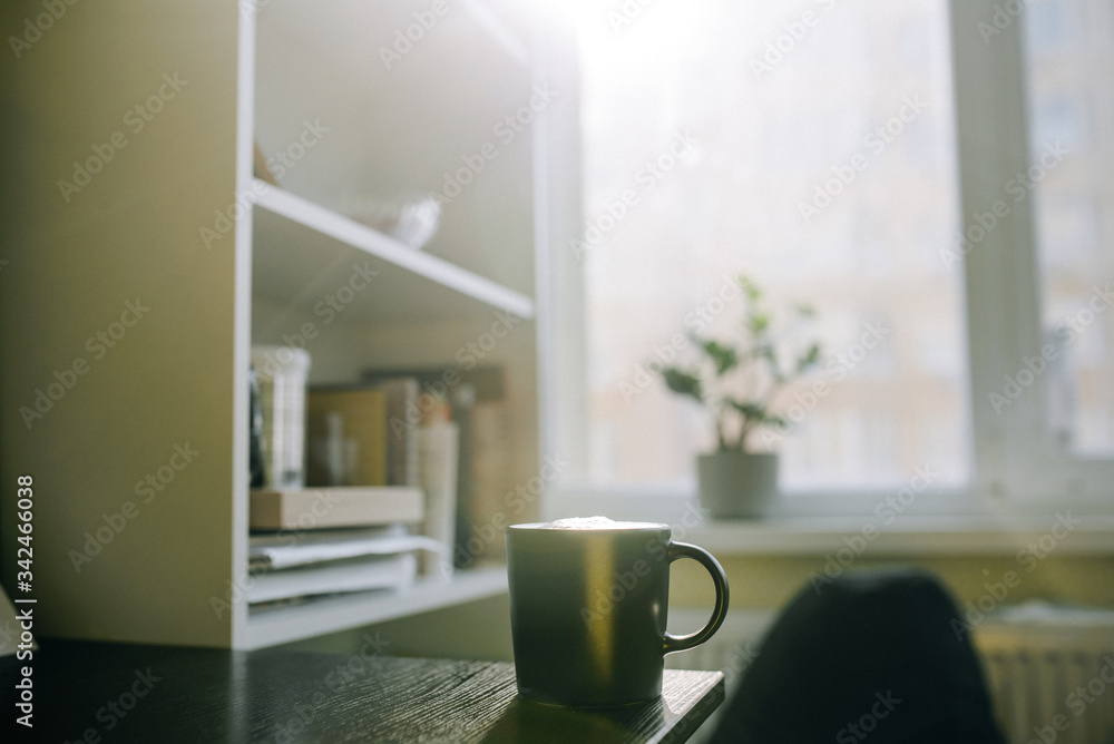 Cup with coffee on table near shelves on window background Cup with coffee on table near shelves on window background