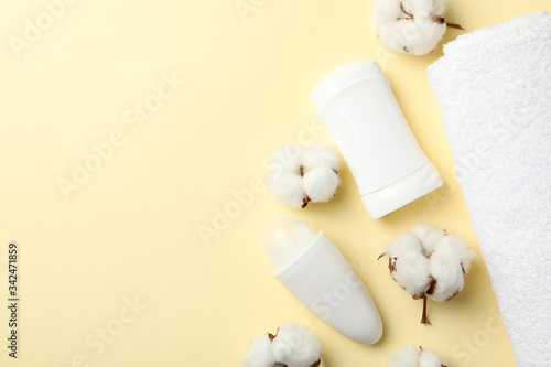 Body deodorants, cotton and towel on beige background, top view