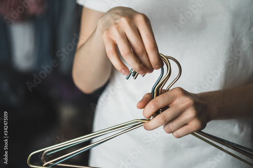 Woman holds metal clothes hangers in hands, at home in the dressing room.