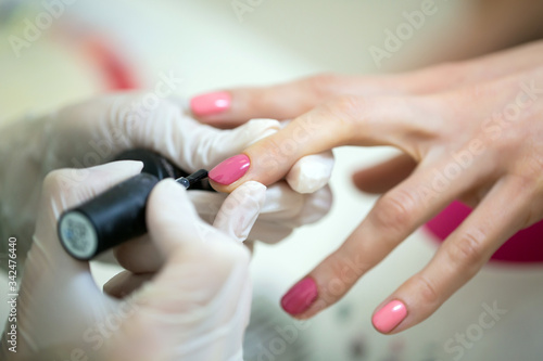 Master during a professional manicure. Master manicurist varnishes the gel on the nails of a female client. The concept of beauty and health.