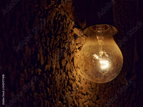 Light bulb on a dark rough stone background. Gloomy dark background.