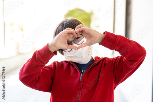 Bambino con occhiali che fa un cuore con le mani, virus quarantena photo