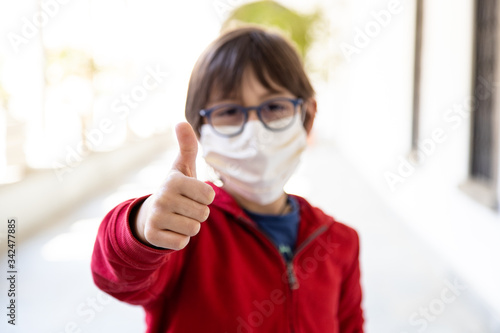 Bambino con occhiali che fa gesto di ok, positivo con la mano, virus quarantena photo