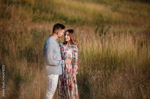young couple resting in nature in a field. couple at sunset