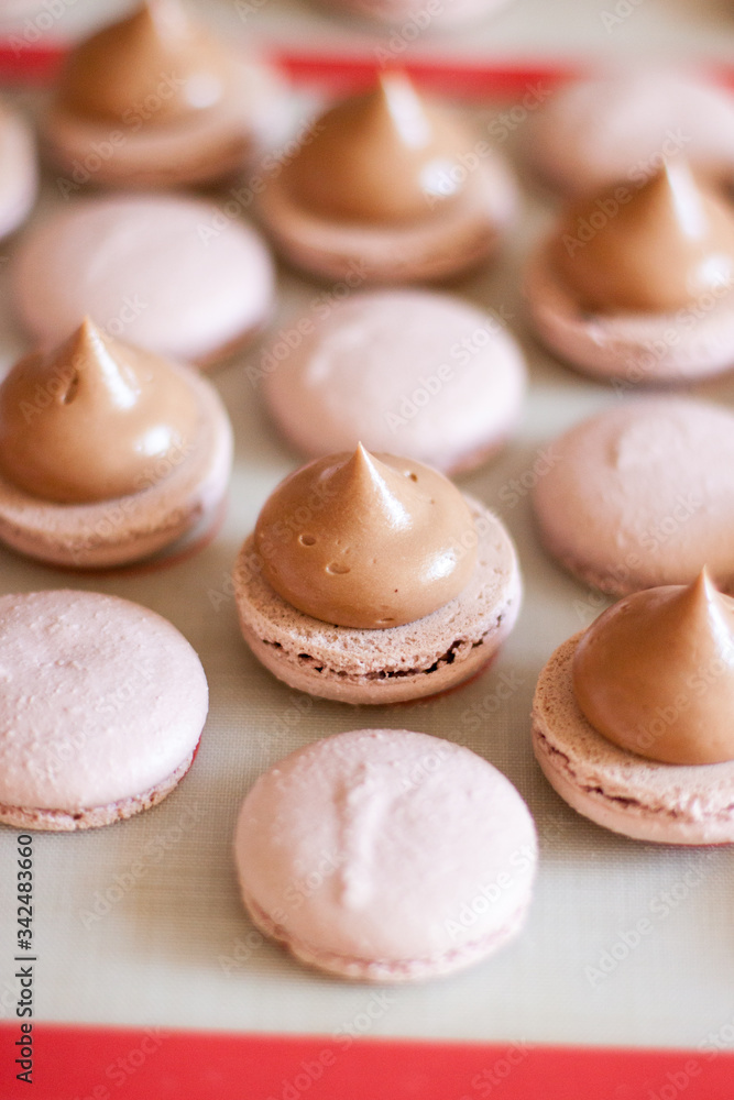 Brown macaroons with chocolate ganache on silicone mat. Cooking process. Selective focus. Brown macaroons with chocolate ganache on silicone mat. Cooking process. Selective focus.