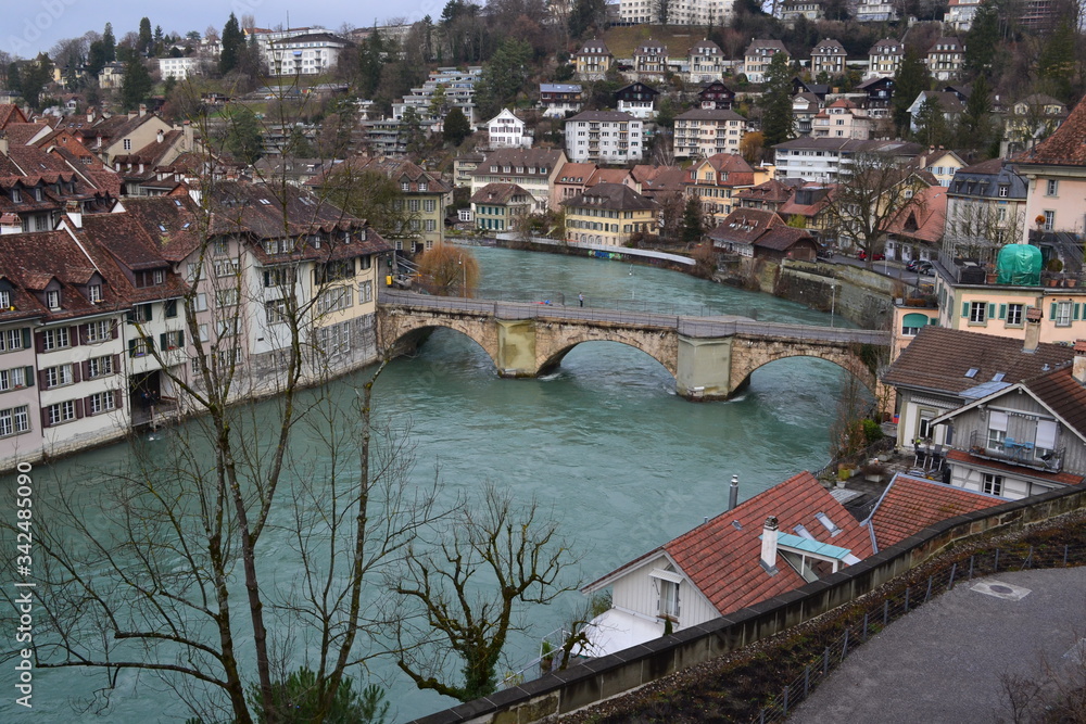 The landscape of Bern, Switzerland, a turbulent river and low-rise buildings on the banks