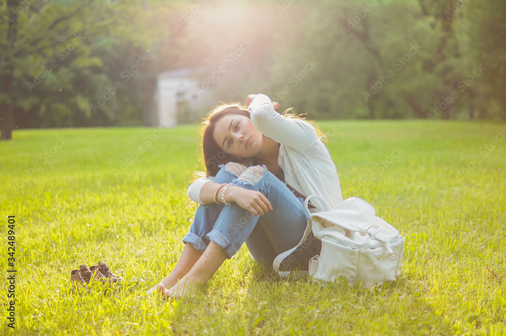 Beautiful girl sits on a meadow with grass in the sunlight. Her mood is joyful, happy, sad and tender. Femininity in all gestures. Happy woman's day. Summer Beautiful girl sits on a meadow with grass in the sunlight. Her mood is joyful, happy, sad and tender. Femininity in all gestures. Happy woman's day. Summer