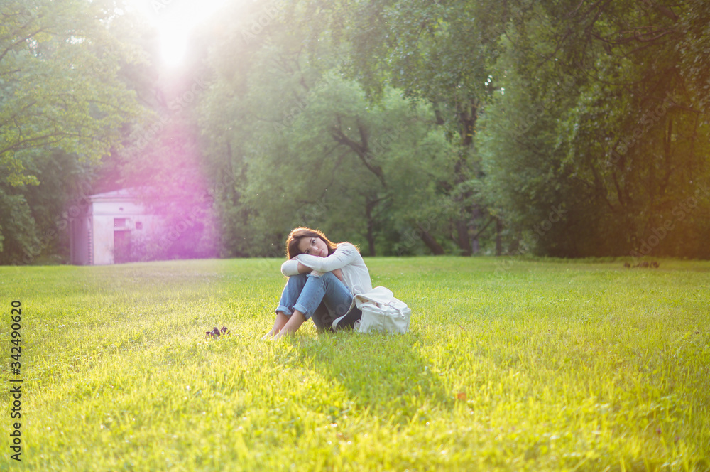 Beautiful girl sits on a meadow with grass in the sunlight. Her mood is joyful, happy, sad and tender. Femininity in all gestures. Happy woman's day. Summer Beautiful girl sits on a meadow with grass in the sunlight. Her mood is joyful, happy, sad and tender. Femininity in all gestures. Happy woman's day. Summer