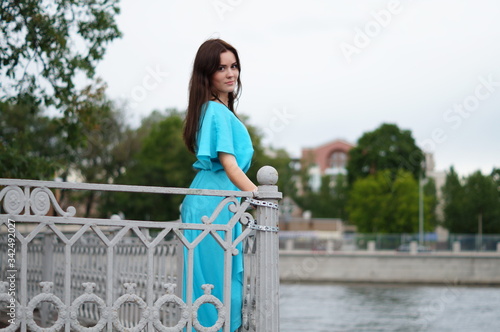 Beautiful girl in a blue long dress posing in a meadow in various elegant poses. Professional model with long hair
