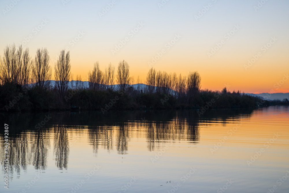 Clear sky Sunset in Ebro river bank whit grass reflections on water