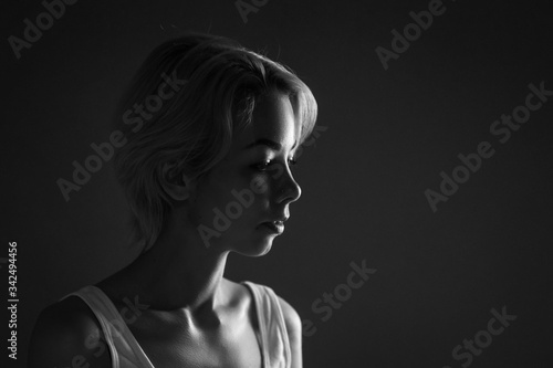 Female portrait close-up looks away, black and white photo dark