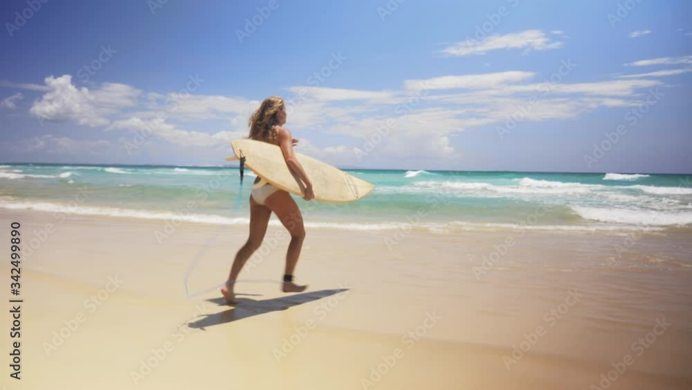 Young Surfer Woman Runs Towards the Ocean on a Clear Beautiful Beach in Australia Young Surfer Woman Runs Towards the Ocean on a Clear Beautiful Beach in Australia