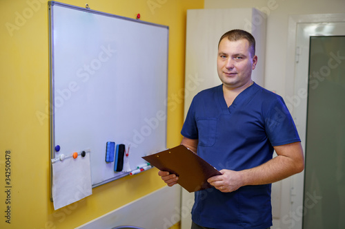 Doctor holding folder in hands. Standing near board. Seminar for doctors. Methods for treating patients.