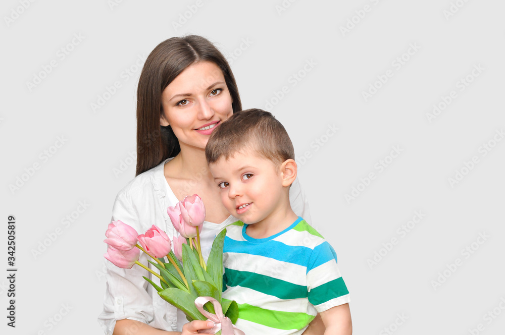 Little child son gives his mother a bouquet of delicate pink tulips. Mother's Day celebration. Little child son gives his mother a bouquet of delicate pink tulips. Mother's Day celebration.
