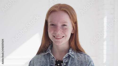 Cheerful smiling face of beautiful teen girl with freckles and red hair