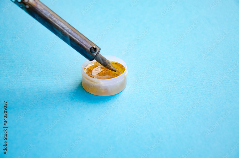 Soldering iron, tin, rosin on a blue background. Soldering iron in male hands. Macro. Repair of electrical equipment, radio engineering. Solder wires, contacts. Copy Space Soldering iron, tin, rosin on a blue background. Soldering iron in male hands. Macro. Repair of electrical equipment, radio engineering. Solder wires, contacts. Copy Space