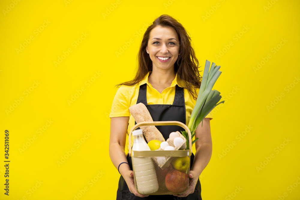 Portrait of happy caucasian farmer with basket of bio groceries and organic farm eco products. Young attractive smiling woman looks at camera, showing box of fresh vegetables and fruits, online food Portrait of happy caucasian farmer with basket of bio groceries and organic farm eco products. Young attractive smiling woman looks at camera, showing box of fresh vegetables and fruits, online food