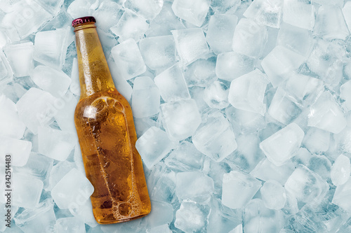 Bottle of cold beer in ice cubes