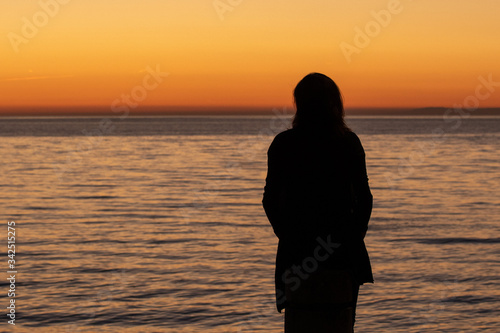 Woman is watching sunset on the beach, Slovenia