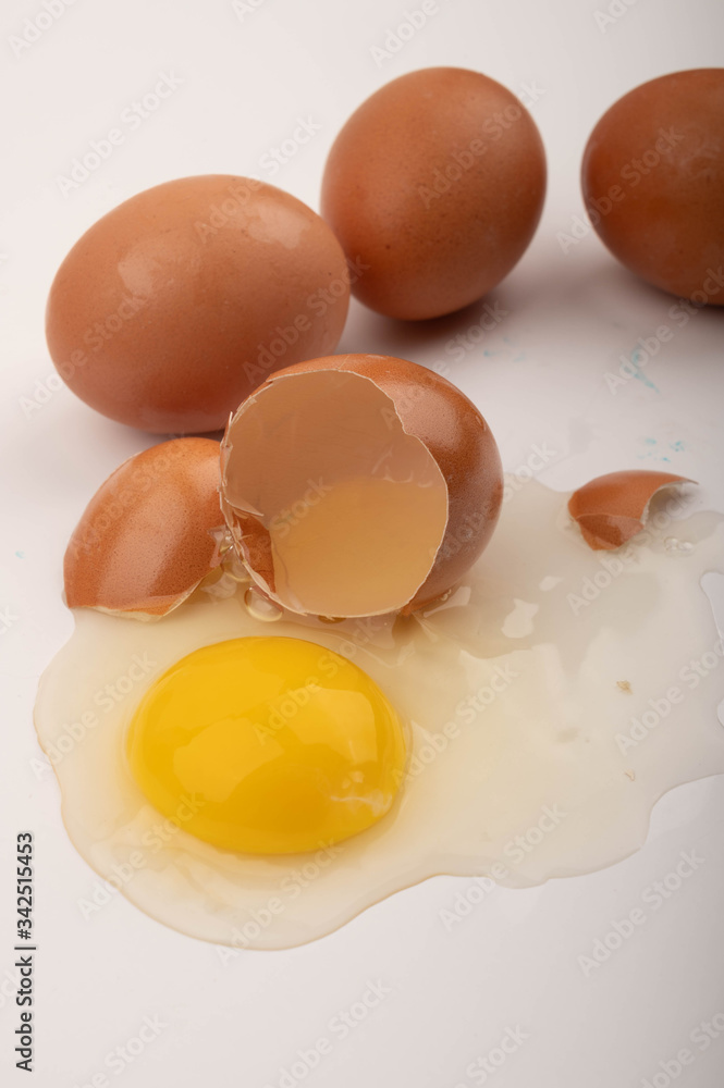A broken chicken egg and scattered eggs on a white background. Close up. A broken chicken egg and scattered eggs on a white background. Close up.