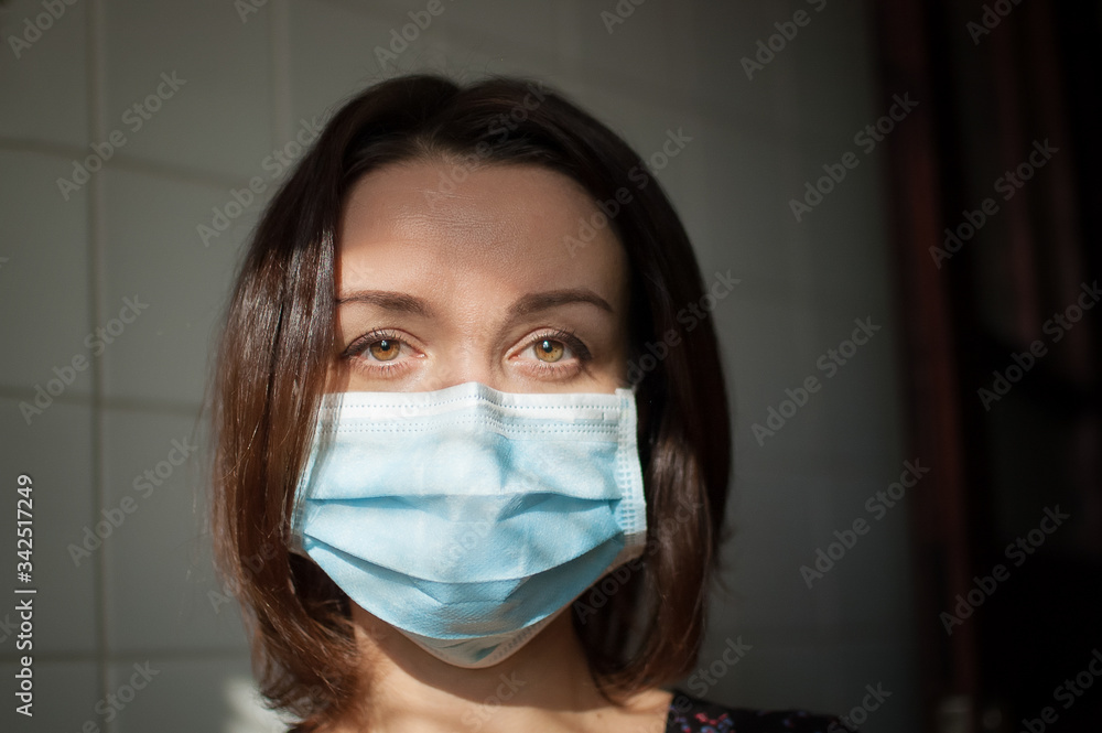 Coronavirus Covid-19 outbreak. Young woman on home isolation wearing surgical mask on the face for protection from virus during pandemia Coronavirus Covid-19 outbreak. Young woman on home isolation wearing surgical mask on the face for protection from virus during pandemia
