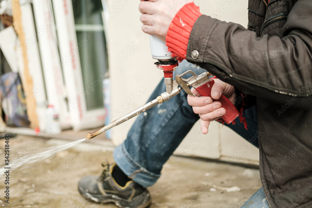 Male hands are holding an old professional gun for aerosol insulating foam, with a balloon and checking its work. Male hands are holding an old professional gun for aerosol insulating foam, with a balloon and checking its work.