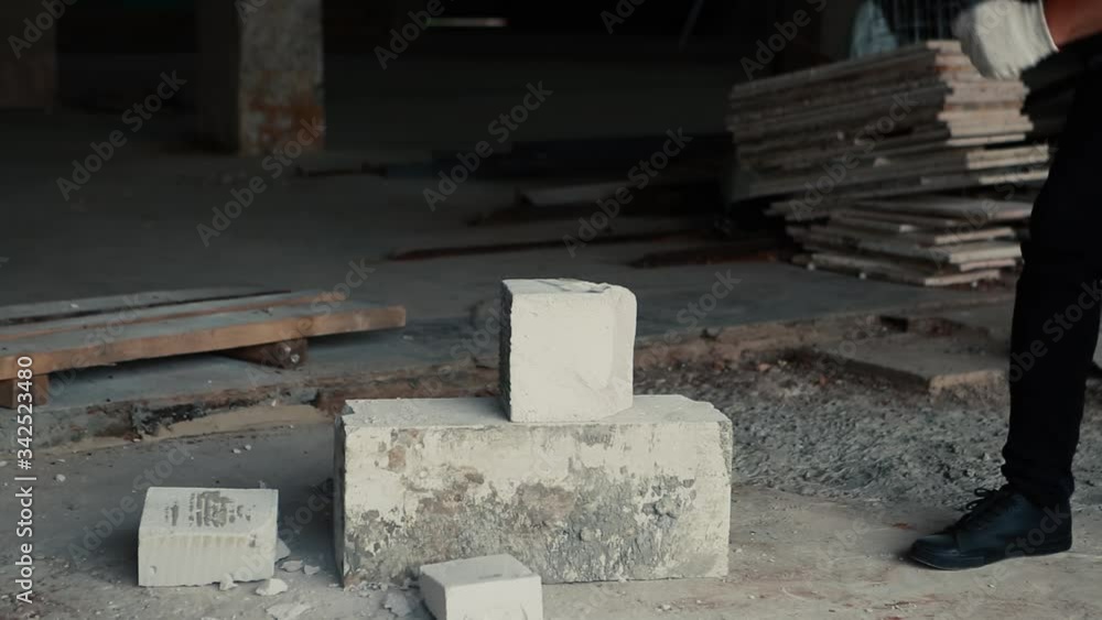 A man in an orange vest hits the cobblestone with a hammer, piercing it. A man in an orange vest hits the cobblestone with a hammer, piercing it.