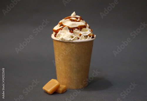 paper cup of coffee with whipped cream and caramel with gray background take away, delivery