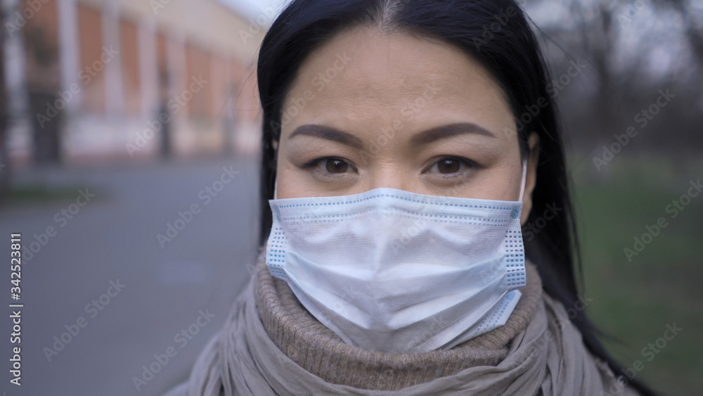 Asian woman in mask standing outdoors, close up Asian woman in mask standing outdoors, close up