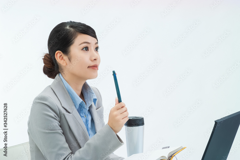 デスクワーク中に手帳を手にいいアイディアが思い浮かんだ若い女性 デスクワーク中に手帳を手にいいアイディアが思い浮かんだ若い女性