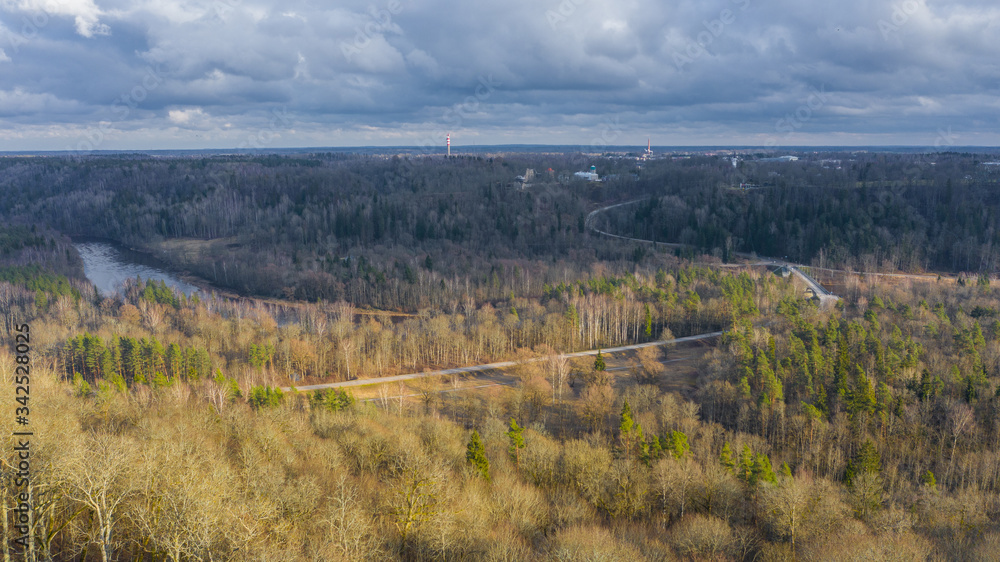 Beautiful panoramic aerial view photo from flying drone over Sigulda city on a sunny winter day without snow against the background of forests and countryside. Sigulda, Latvia (series)