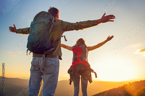 Couple with raised arms holding hands and looking at sunset