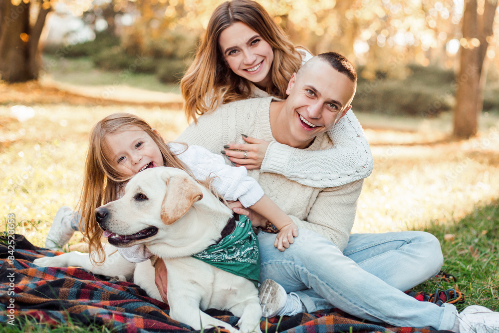 Happy beautiful family with dog labrador is having fun are sitting on green grass in park. Happy beautiful family with dog labrador is having fun are sitting on green grass in park.