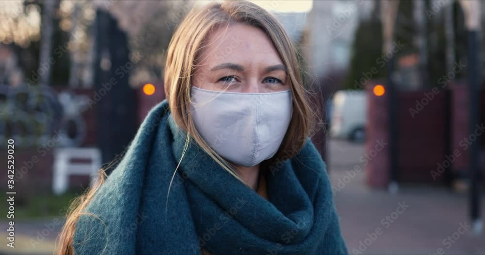 Epidemic protection. Portrait of young happy blonde woman wearing mask on face outdoors during COVID-19 quarantine. Epidemic protection. Portrait of young happy blonde woman wearing mask on face outdoors during COVID-19 quarantine.