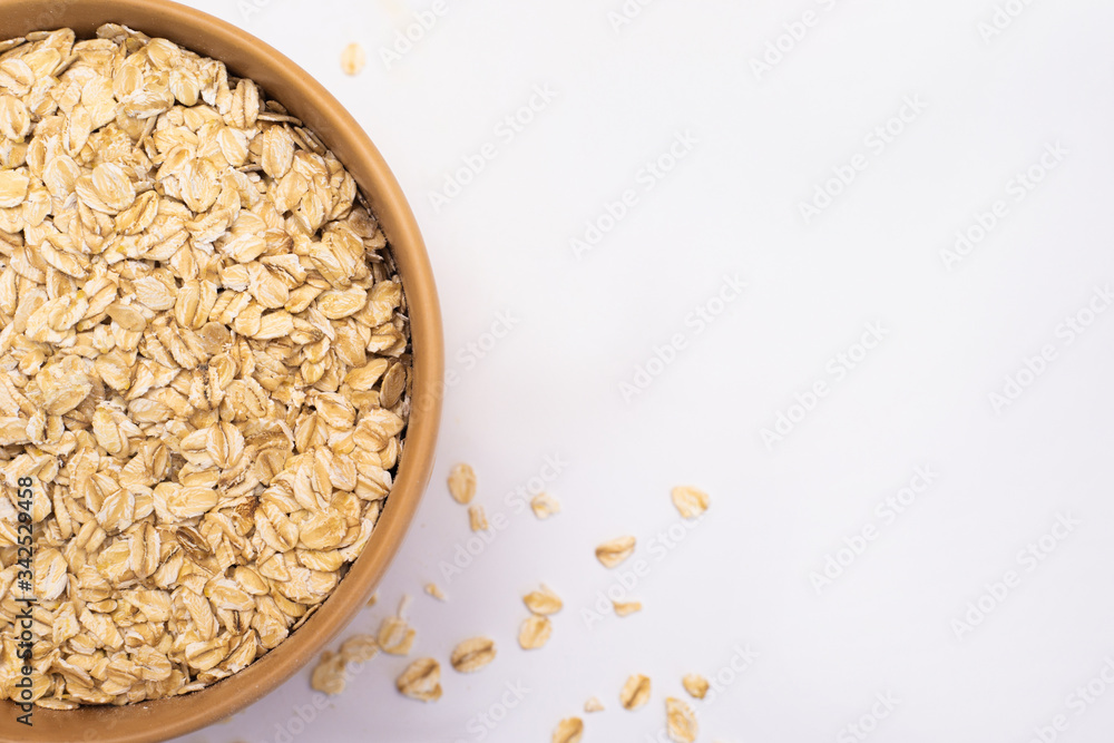 Oatmeal in a plate and scattered on a white background. The view from top. Copy space. Oatmeal in a plate and scattered on a white background. The view from top. Copy space.