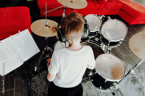 Fototapeta Young boy learning playing drums at home