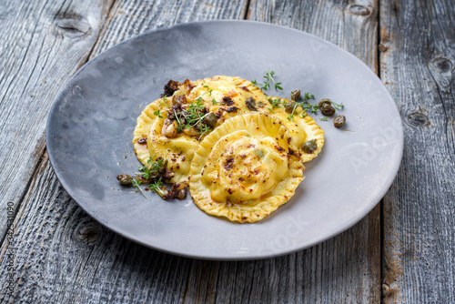 Traditionelle italienische Ravioli Pasta angeboten mit Kapern und Zwiebel Chili Pesto als closeup auf einem Modern Design Teller photo