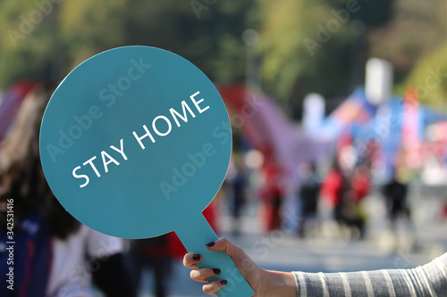 A girl with a paper with stay at home holding on hand