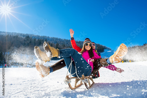 Young happy couple sledding in winter at ski center