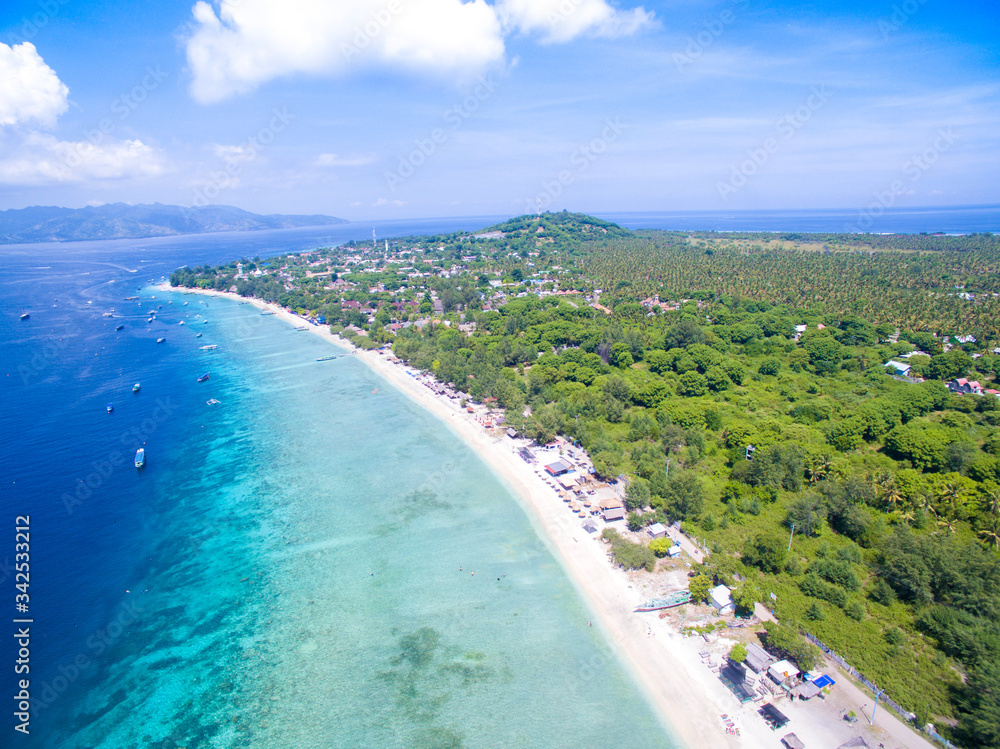Tropical empty sandy beach, turquoise water with boats in gili trawangan lombok