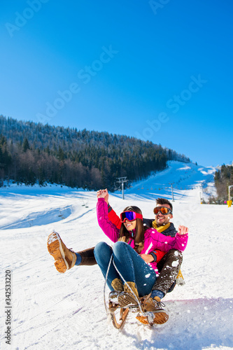 Young Happy Couple On Sledge Having Fun