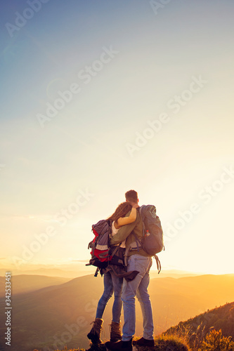Hikers with backpacks relaxing on top of a mountain and enjoying the view of valley © FS-Stock