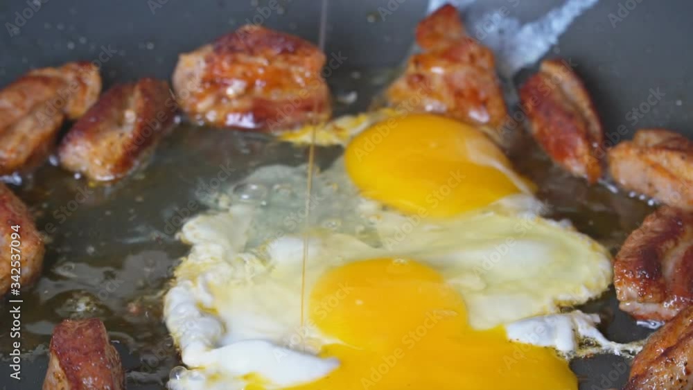 Two chicken eggs fried grilled pork ribs on roasting in a cooking pan slow motion Two chicken eggs fried grilled pork ribs on roasting in a cooking pan slow motion