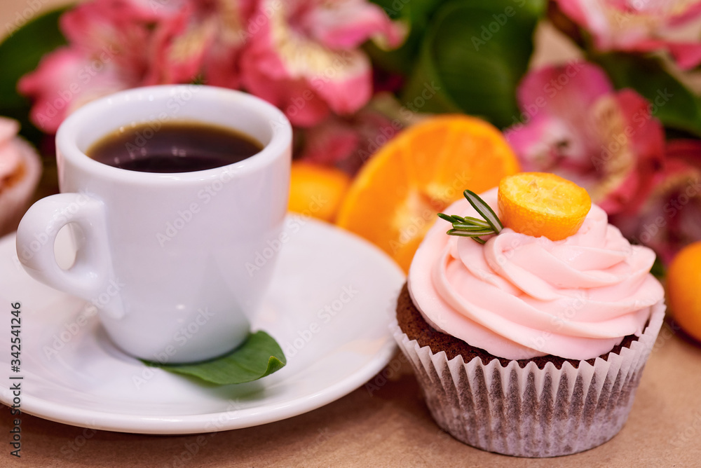 Chocolate cupcakes with kumquat. Cupcakes and a cup of coffee on the table with flowers. Selective focus. Chocolate cupcakes with kumquat. Cupcakes and a cup of coffee on the table with flowers. Selective focus.